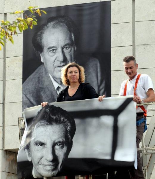 Amélie Debray entre deux portraits à faire adhérer sur la façade malgré la pluie. - (Photo NR, Jérôme Dutac)